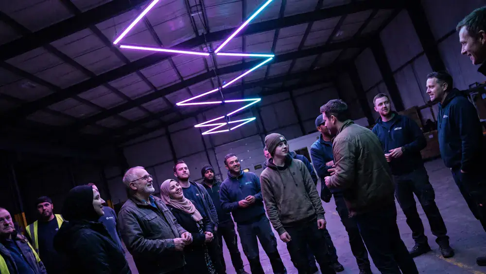 Dark Matter Berlin – Kollegen stehen staunend als Gruppe unter einer kinetischen Lichtinstallation in Lichtenberg