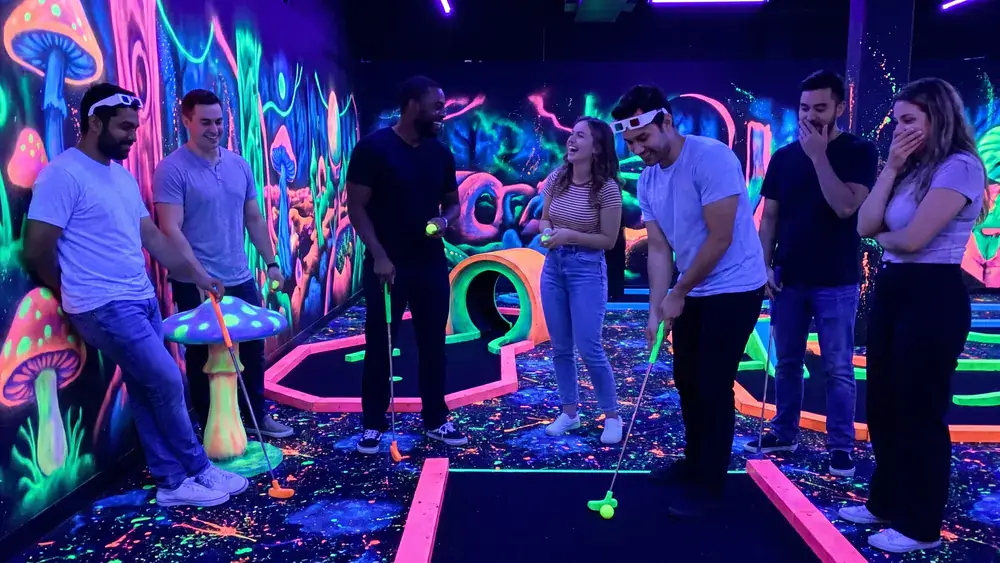 Schwarzlicht-Minigolf in Berlin – Kollegen spielen als Gruppe mit 3D-Brillen Minigolf in leuchtender Neonwelt im DockX Tempelhof