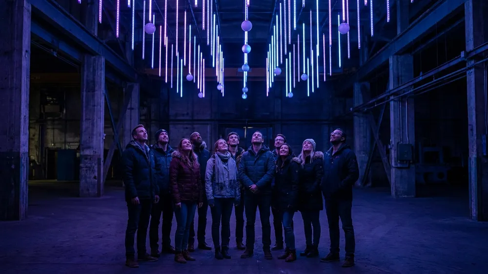 Dark Matter Berlin – Gruppe steht staunend unter einer kinetischen Lichtinstallation in Oberschöneweide