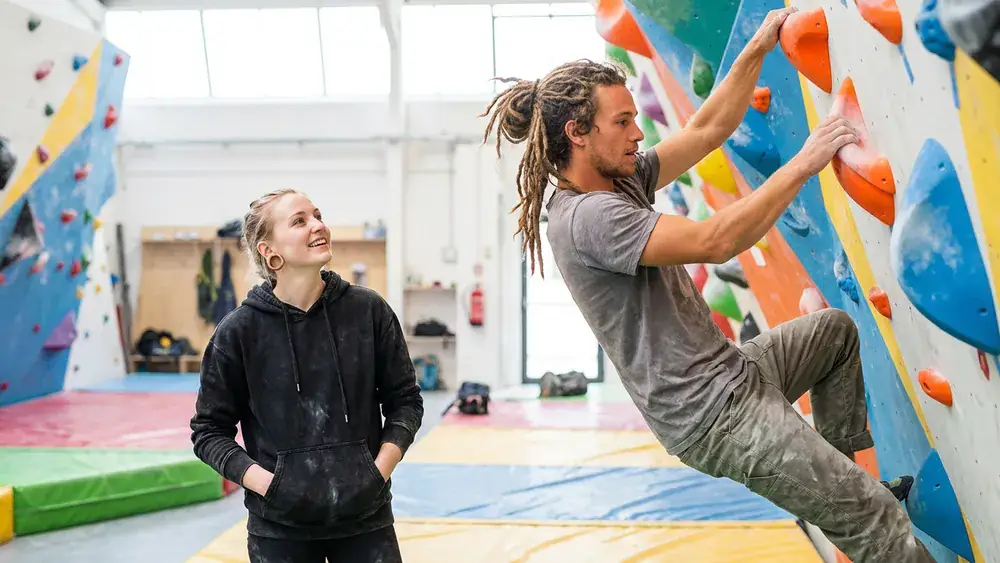 Südbloc Boulderhalle Berlin – Zwei Personen klettern an bunten Griffen in der lichtdurchfluteten Halle