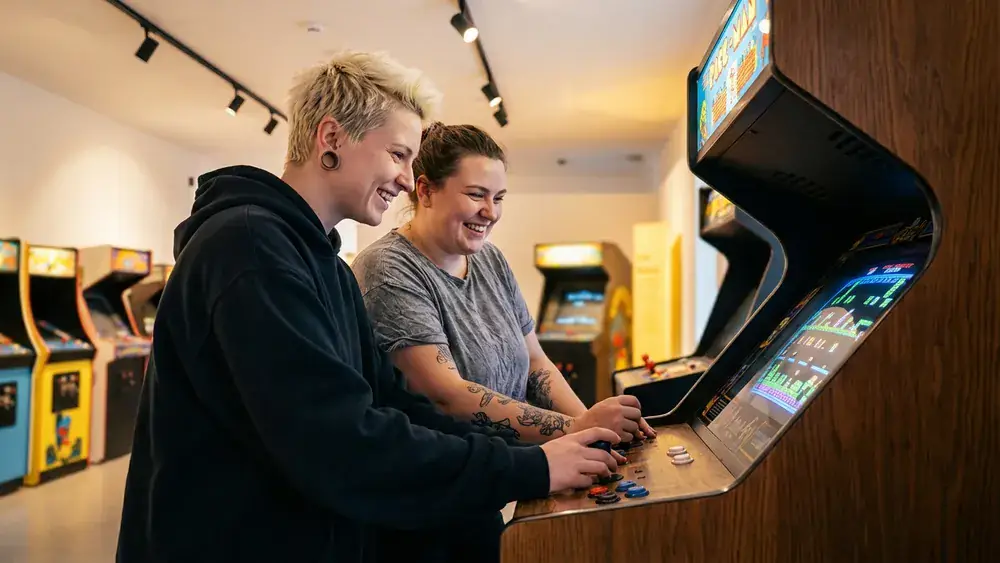 Computerspielemuseum Berlin – Zwei Personen spielen an einem Retro-Arcade-Automaten