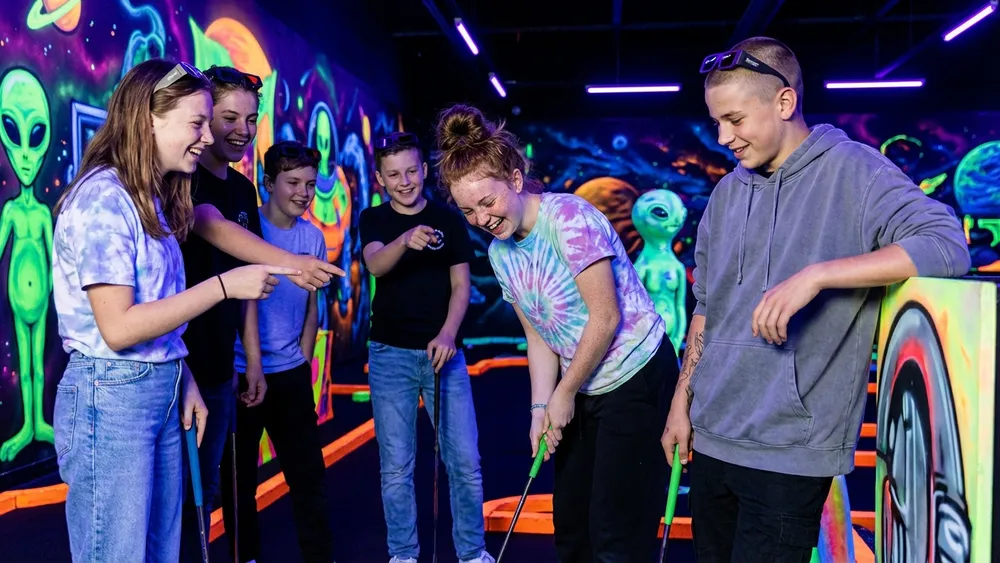 Schwarzlicht-Minigolf in Berlin – Schulklasse spielt Minigolf unter leuchtendem Schwarzlicht