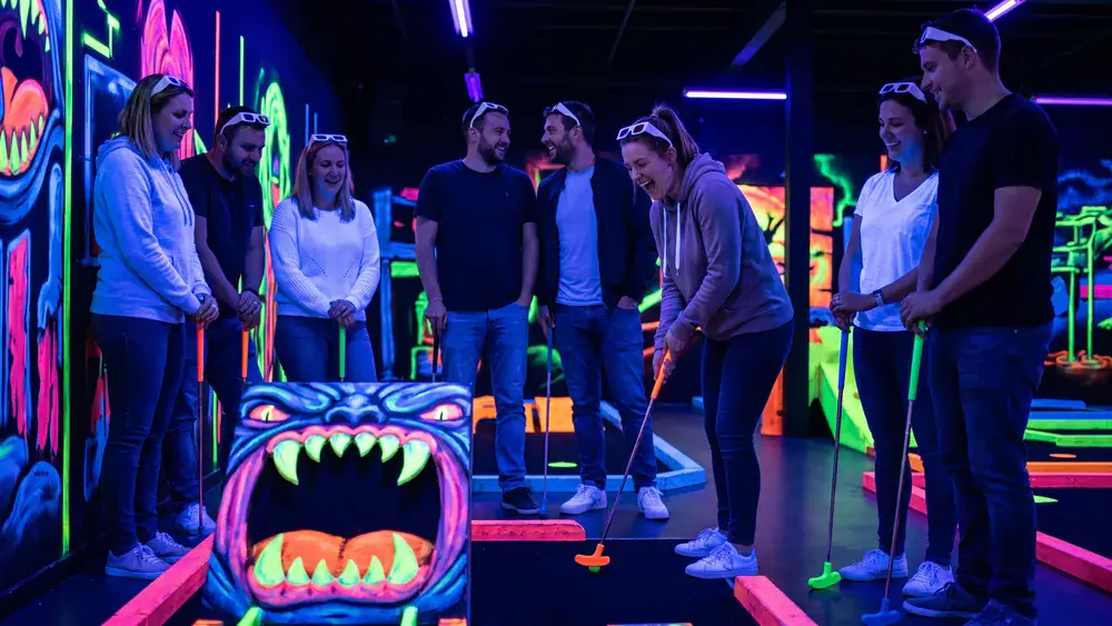 Schwarzlicht-Minigolf in Berlin – Kollegen spielen mit 3D-Brillen in leuchtender Neonwelt im DockX Tempelhof