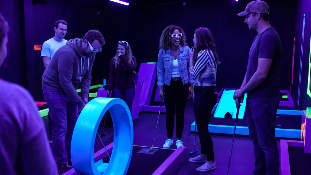 Schwarzlicht Minigolf in Bielefeld – Kollegen spielen mit 3D-Brillen Minigolf in leuchtender Neonwelt
