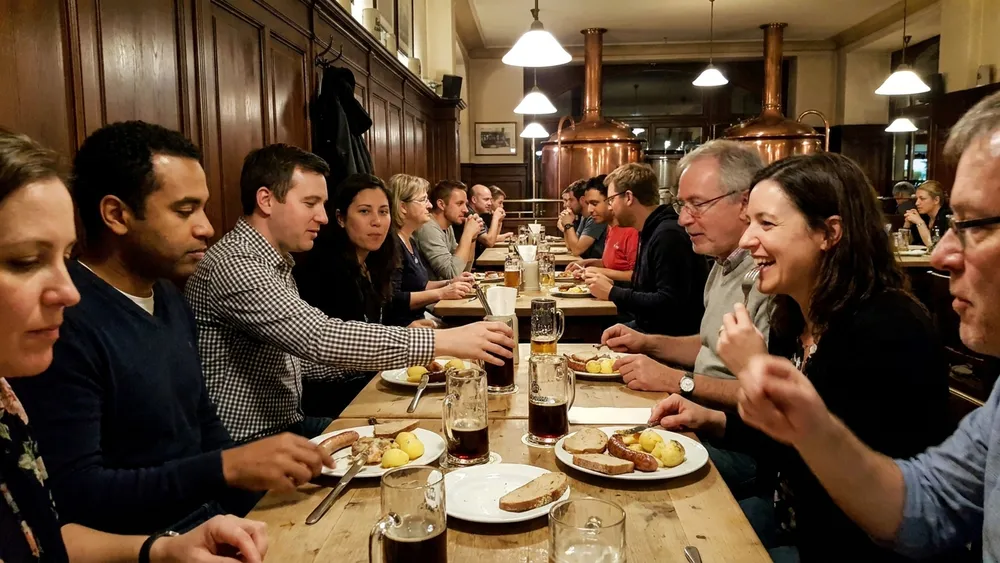 Brauhaus in Bielefeld – Gruppe trinkt Hausbier an langen Tischen mit Kupferkesseln im Hintergrund in der Altstadt