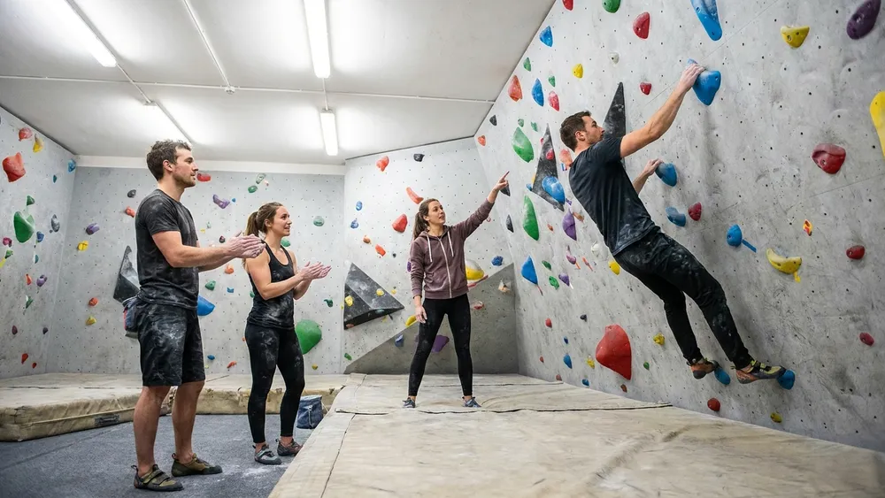 Boulderhalle in Bielefeld - Erwachsene klettern an bunten Griffen an der Wand
