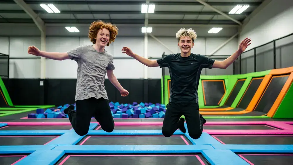 Superfly Bielefeld – Zwei Personen springen auf Trampolinen in einem bunten Indoor-Park