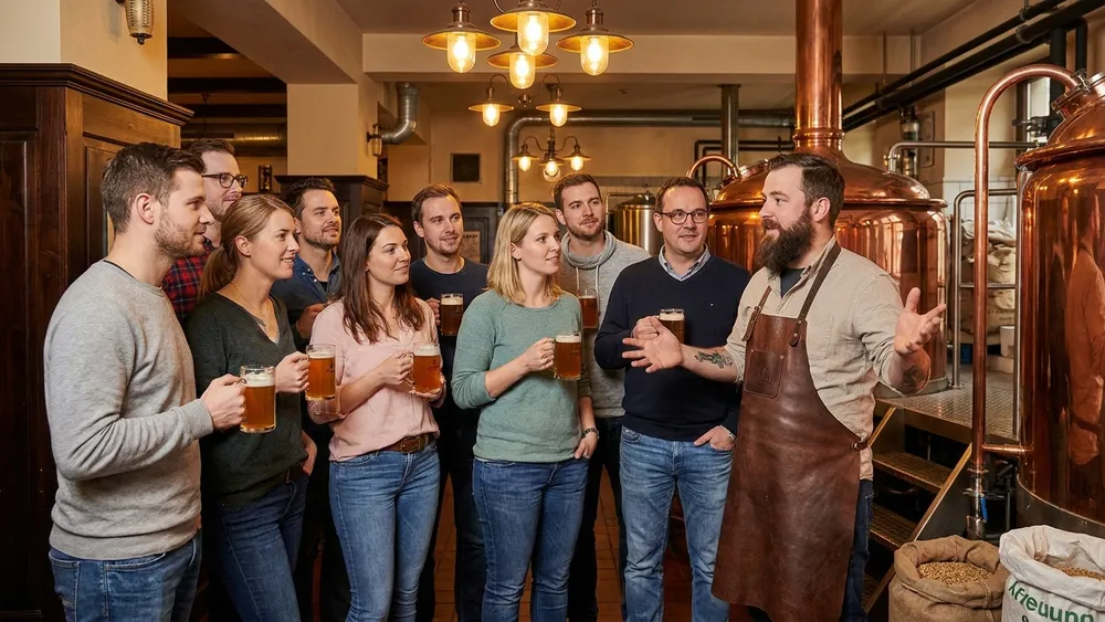 Brauereiführung in Bielefeld – Team an Kupferkesseln mit Brauer im Joh. Albrecht Brauhaus