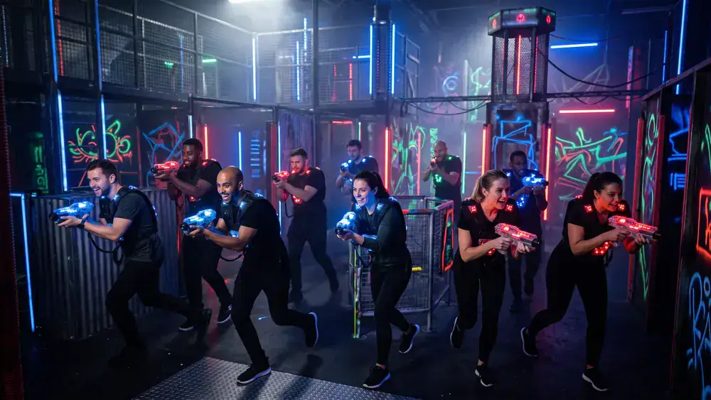 Lasertag in Bielefeld – Kollegen in taktischen Westen spielen zur Weihnachtsfeier in einer dunklen Neon-Arena in Stieghorst