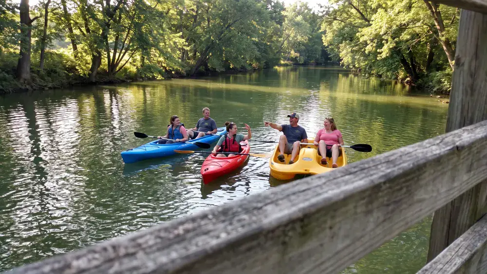 Bootsverleih auf der Oker in Braunschweig – Kollegen paddeln in mehreren Kajaks durch grüne Ufer