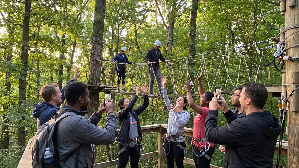 Hochseilgarten in Braunschweig – Kollegen klettern in Gurten durch Seilbrücken zwischen Bäumen im Westpark