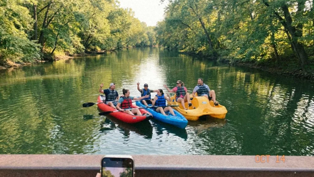 Bootsverleih auf der Oker in Braunschweig – Gruppe paddelt in mehreren Kajaks durch grüne Ufer