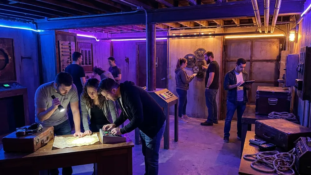 Mind Arena in Braunschweig – Gruppe löst Rätsel an mehreren beleuchteten Stationen in einer großen Escape-Game-Halle