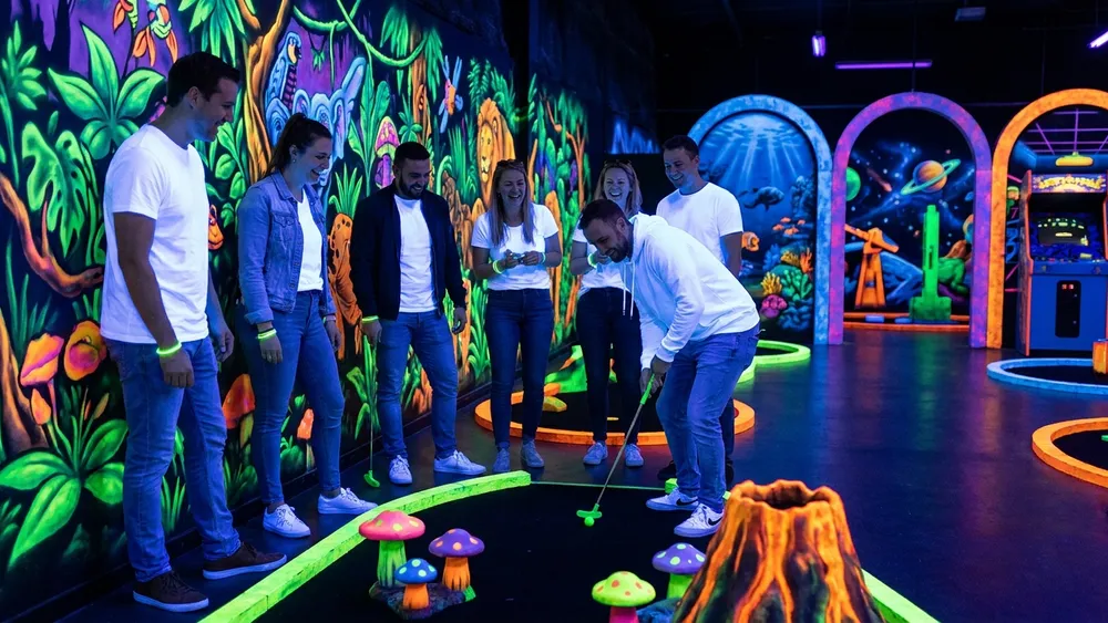 Schwarzlicht Minigolf in Braunschweig – Gruppe spielt Minigolf unter UV-Licht zwischen leuchtenden Graffiti-Wänden