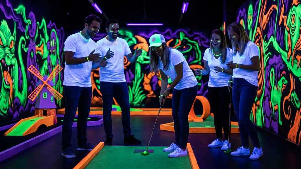 Schwarzlichtlöwen Minigolf in Braunschweig - Erwachsene spielen Minigolf unter UV-Licht
