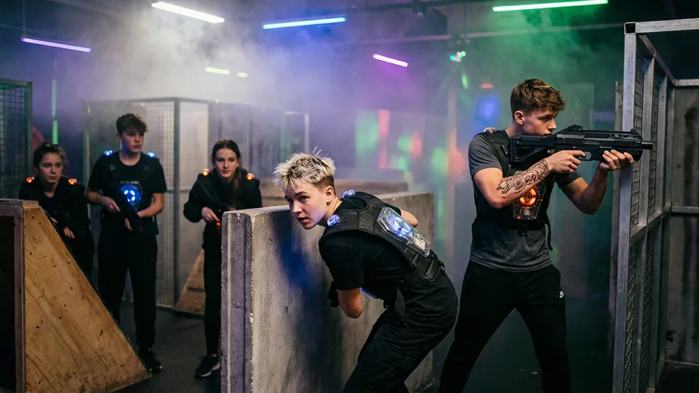 Lasertag in Braunschweig – Schüler mit Laserpistolen in einer dunklen Arena mit Neonlicht und Nebeleffekten
