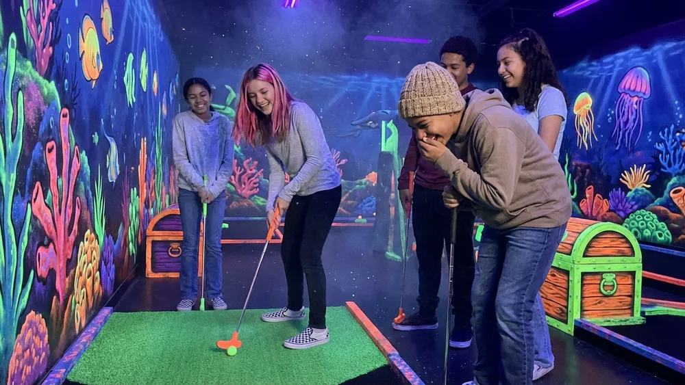 Schwarzlicht Minigolf in Braunschweig – Schüler spielen auf leuchtenden Bahnen unter UV-Licht