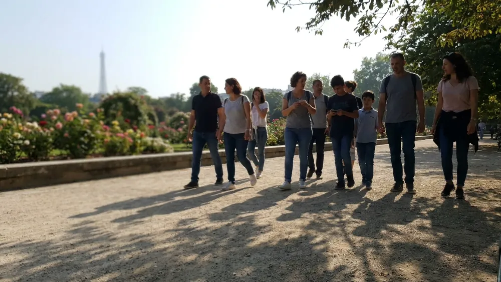 Westfalenpark in Dortmund – Gruppe spaziert bei Sonnenschein vorbei am Rosengarten mit Florianturm im Hintergrund