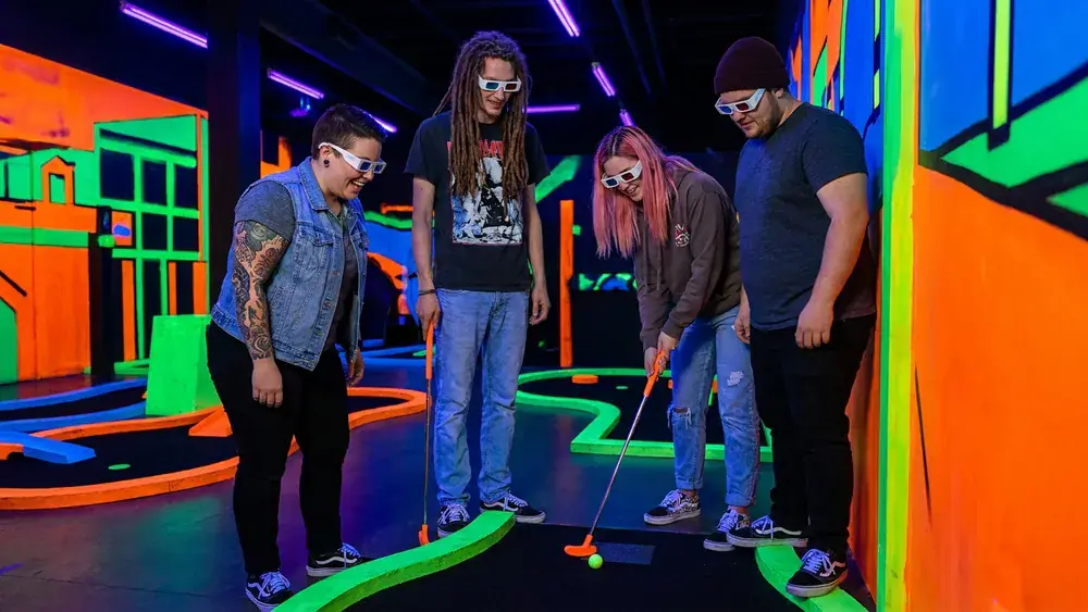 Glowing Rooms in Dortmund – Gruppe spielt Schwarzlicht-Minigolf mit 3D-Brillen