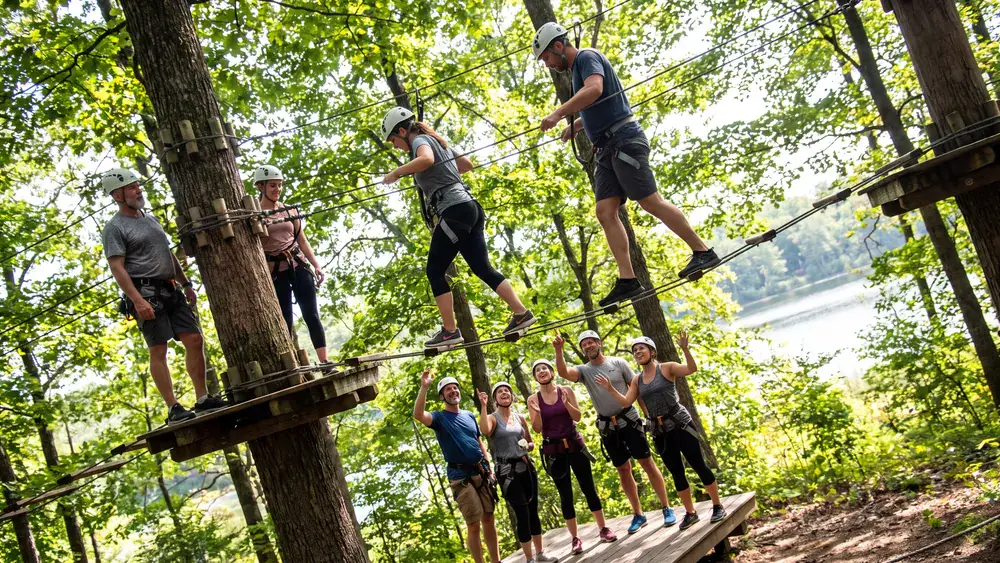 Hochseilgarten tree2tree in Dortmund – Team klettert mit Helmen und Gurten durch einen Parcours in den Bäumen