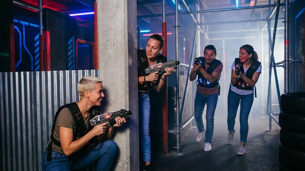 LaserTag Evolution Düsseldorf - Erwachsene in einer dunklen Arena mit Neonlichtern