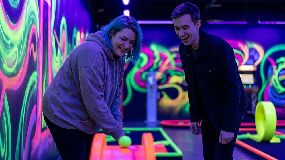 Schwarzlicht Minigolf in Düsseldorf - Erwachsene spielen Minigolf in leuchtender 3D-Neonwelt