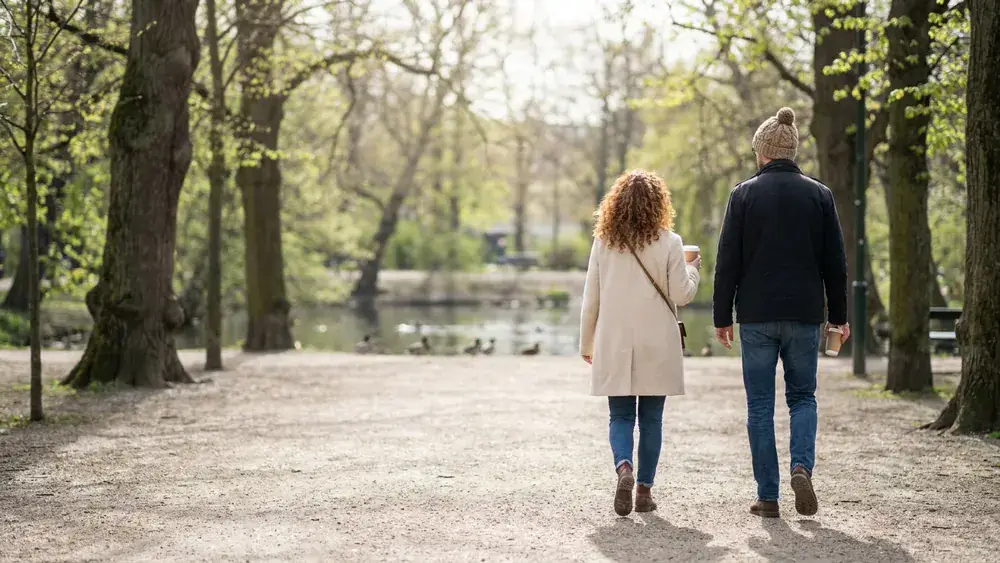 Hofgarten in Düsseldorf – Zwei Personen spazieren auf dem Weg durch den Park mit alten Bäumen