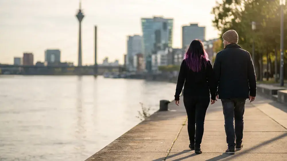 Rheinuferpromenade in Düsseldorf – Spaziergänger am Rhein mit Blick auf den Rheinturm