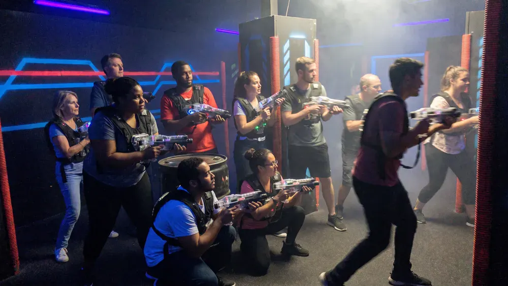 Lasertag in Hamburg – Kollegen mit Sensorwesten spielen in einer dunklen Neon-Arena im Othmarschen Park