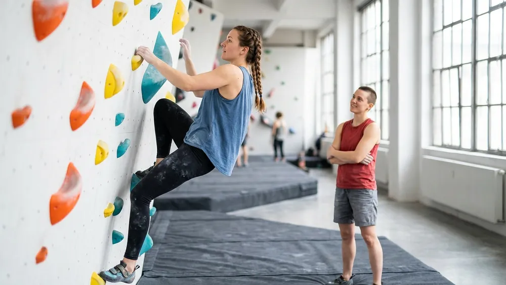 Bouldern in Hamburg – Zwei Personen klettern und sichern an einer farbigen Indoor-Boulderwand