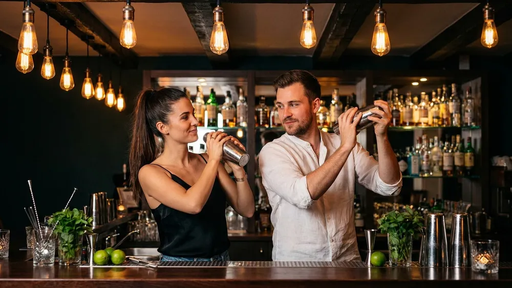 Cocktailkurs in Hamburg – Zwei Personen mixen Cocktails hinter einer beleuchteten Bar