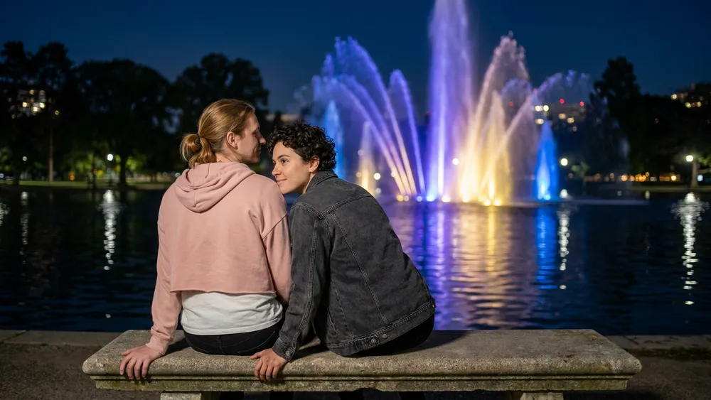 Wasserlichtkonzerte in Planten un Blomen Hamburg – Zwei Personen schauen auf farbig beleuchtete Wasserfontänen am Parksee