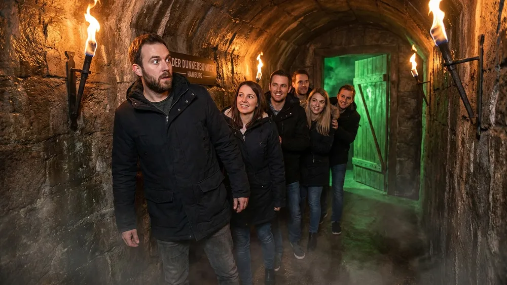 Hamburg Dungeon - Erwachsene in einem dunklen mittelalterlichen Tunnel mit Fackellicht in der Speicherstadt