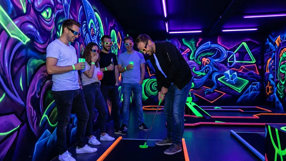 Schwarzlicht-Minigolf in Hamburg - Erwachsene spielen mit 3D-Brillen unter Neonlicht in Stellingen
