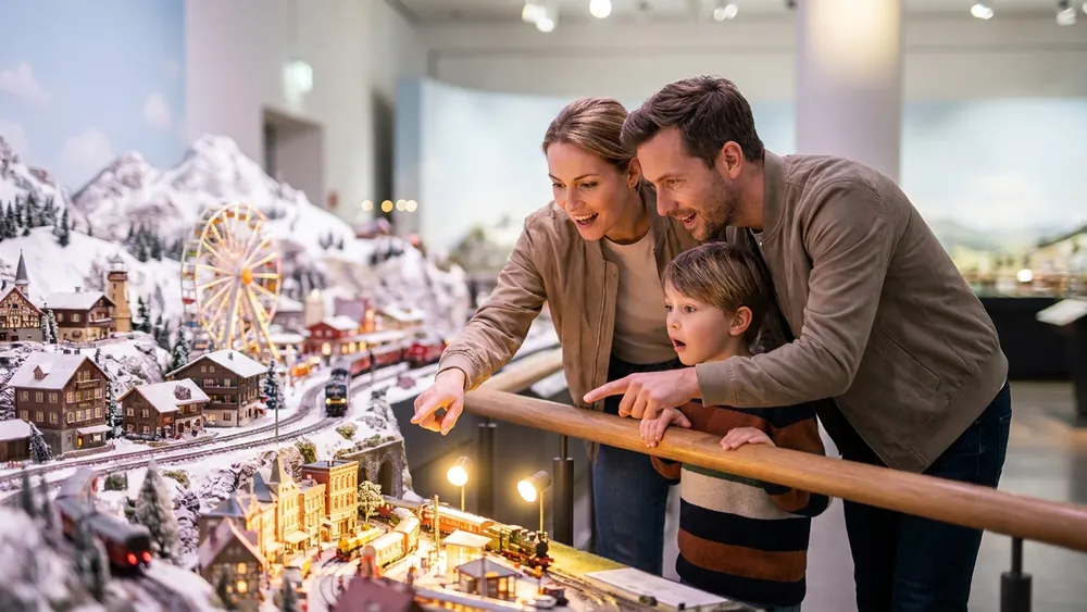 Miniatur Wunderland Hamburg – Familie betrachtet ein detailliertes Modelllandschafts-Diorama mit Mini-Zügen