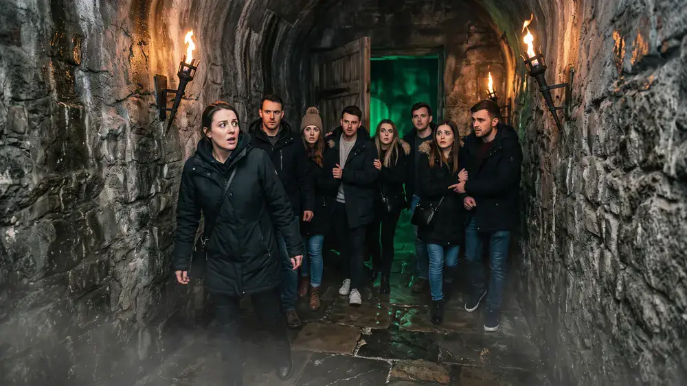 Hamburg Dungeon – Kollegenrunde in einem dunklen mittelalterlichen Tunnel mit Fackellicht in der Speicherstadt