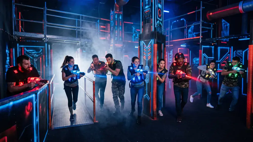 Lasertag in Hamburg – Kollegen mit Sensorwesten spielen in einer dunklen Neon-Arena im Othmarschen Park