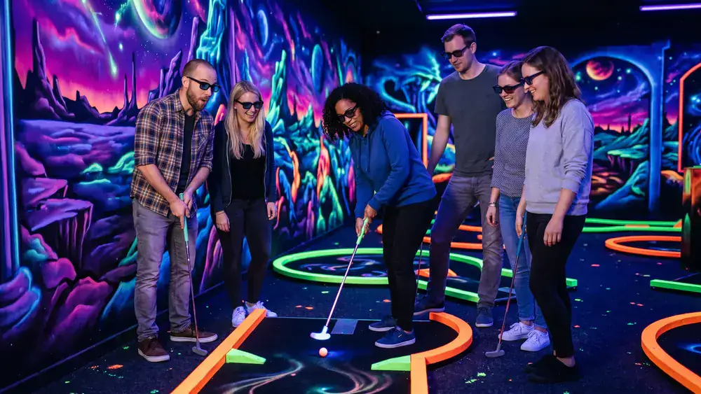 Schwarzlicht-Minigolf in Hamburg – Kollegen spielen mit 3D-Brillen unter Neonlicht in Stellingen