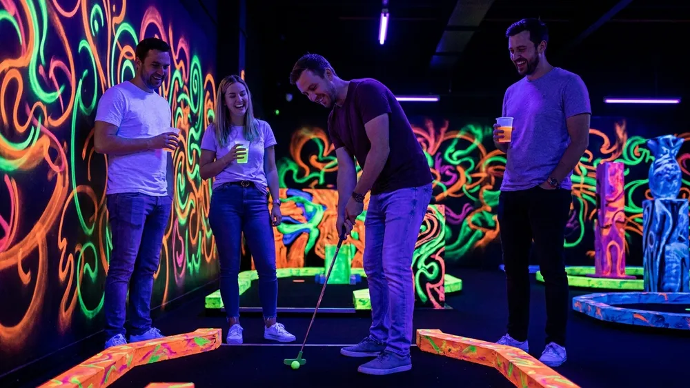 Schwarzlicht Minigolf in Hannover - Erwachsene spielen Neon-Minigolf in bunter UV-Atmosphäre