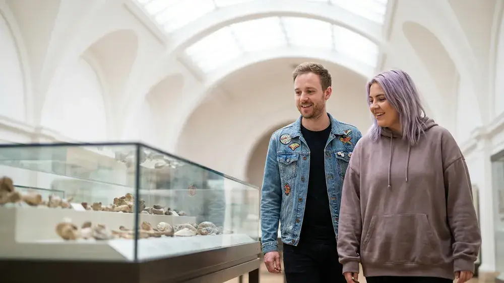 Landesmuseum Hannover – Zwei Personen betrachten ein Dinosaurier-Skelett in einer hellen Ausstellungshalle