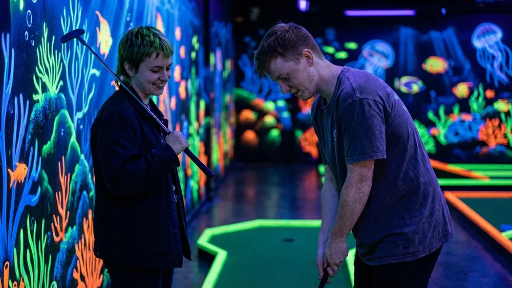 4D Schwarzlicht Minigolf in Kiel – Zwei Personen spielen Minigolf in leuchtenden Neonfarben
