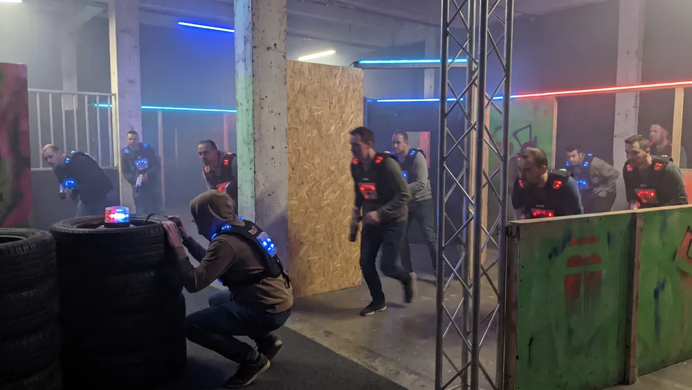 Lasertag in Kiel – Kollegen mit Sensorwesten spielen in einer dunklen Neon-Arena