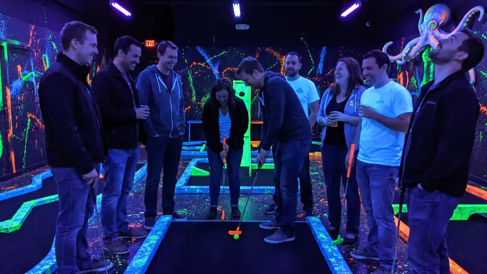 4D Schwarzlicht Minigolf in Kiel – Kollegen spielen Minigolf in leuchtenden Neonfarben
