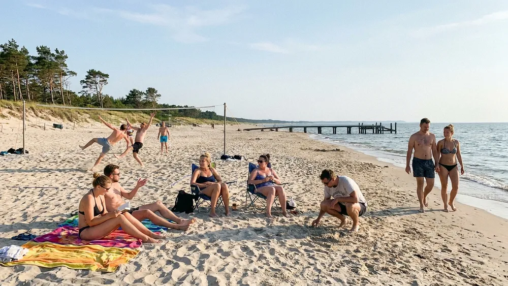 Falckensteiner Strand in Kiel – Gruppe sitzt und spielt Beachvolleyball am langen Ostseestrand