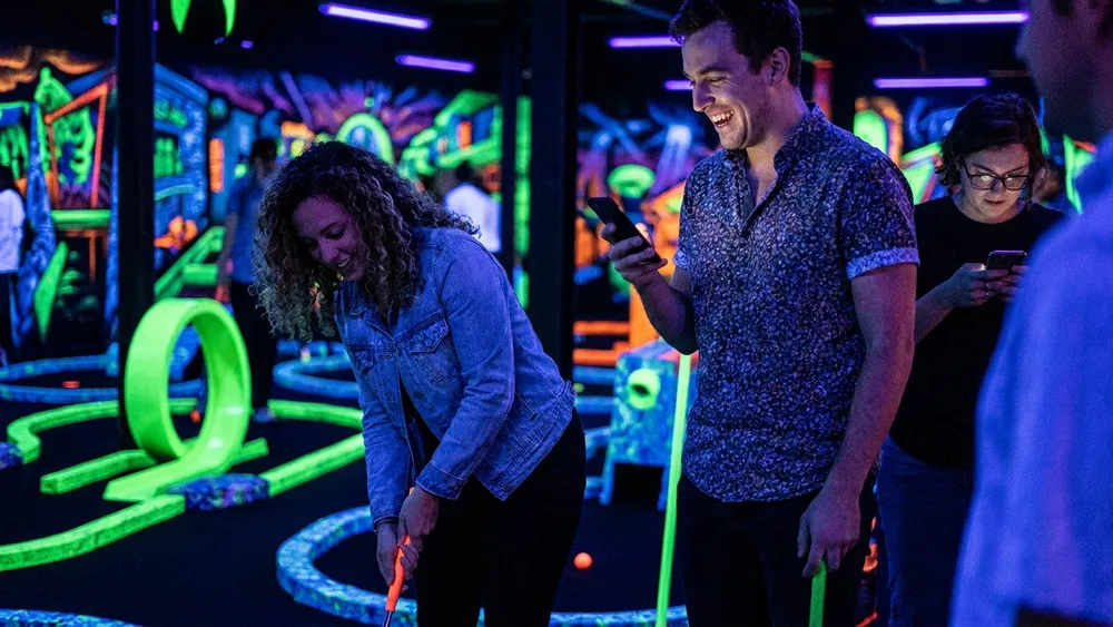 4D Schwarzlicht Minigolf in Kiel – Gruppe spielt Minigolf in leuchtenden Neonfarben
