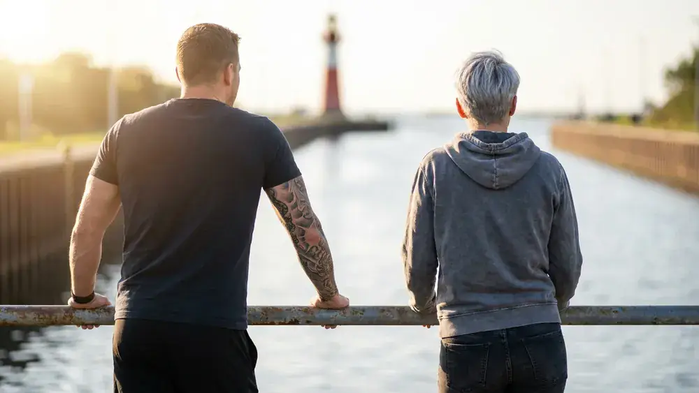 Tiessenkai in Kiel-Holtenau – Zwei Personen blicken auf den Nord-Ostsee-Kanal mit Leuchtturm