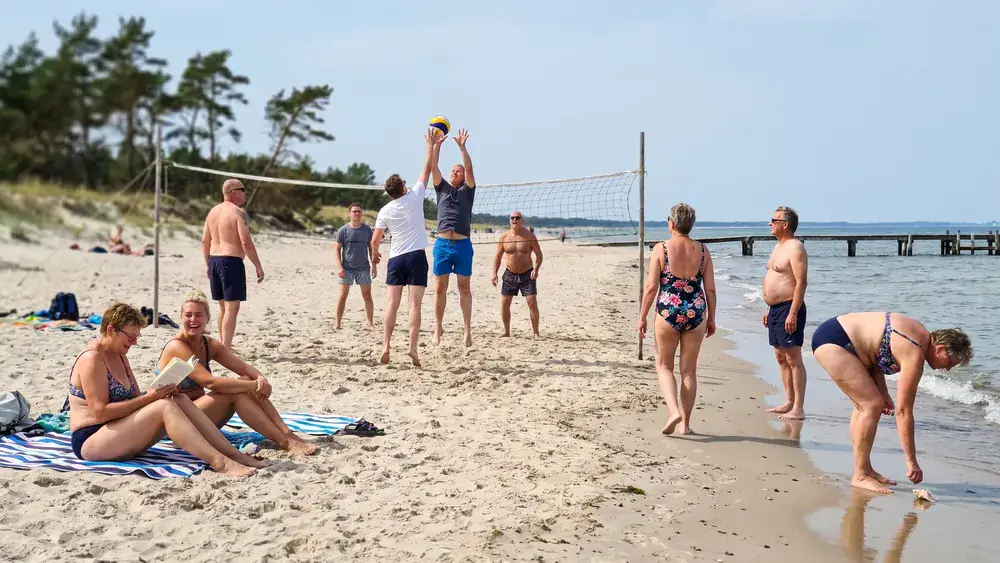 Falckensteiner Strand in Kiel – Kollegen sitzen und spielen Beachvolleyball am langen Ostseestrand