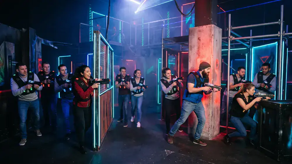 Lasertag in Kiel – Kollegen in Westen spielen zur Weihnachtsfeier in einer dunklen Neon-Arena