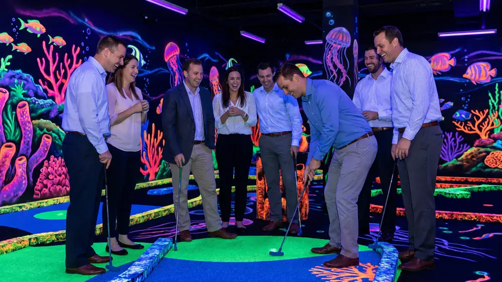 Schwarzlicht Minigolf in Kiel – Kollegen spielen Minigolf in leuchtenden Neonfarben zur Weihnachtsfeier