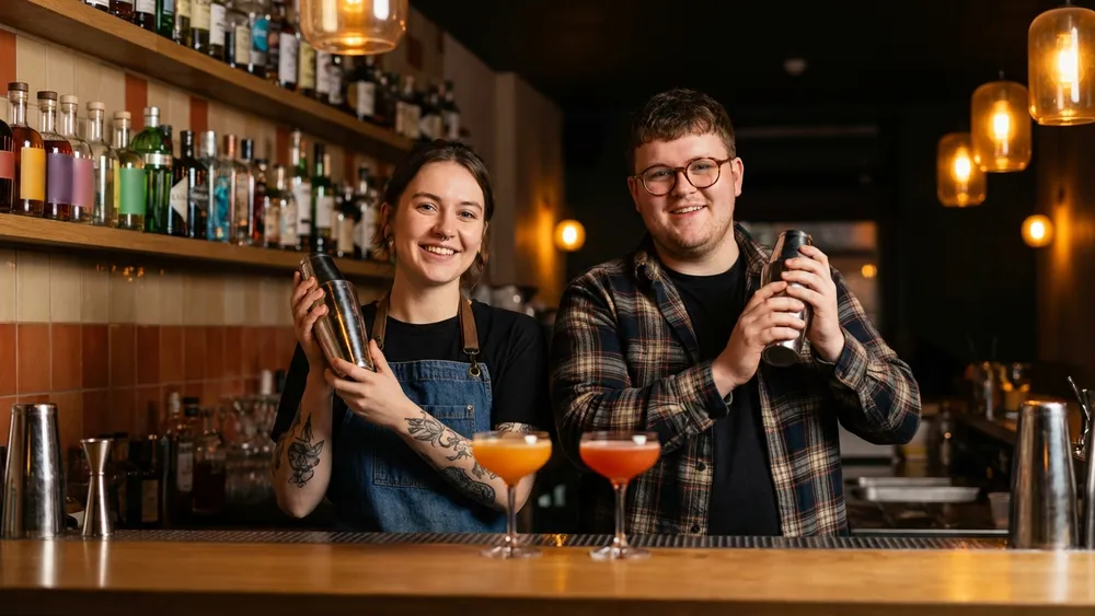 Cocktailkurs in Köln – Zwei Personen mixen Cocktails an einer Bar unter Anleitung